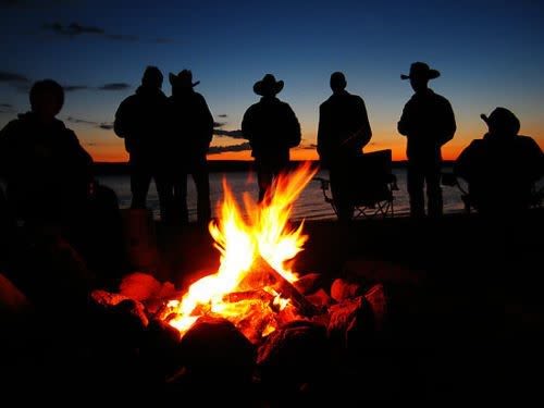 Men meeting around campfire.